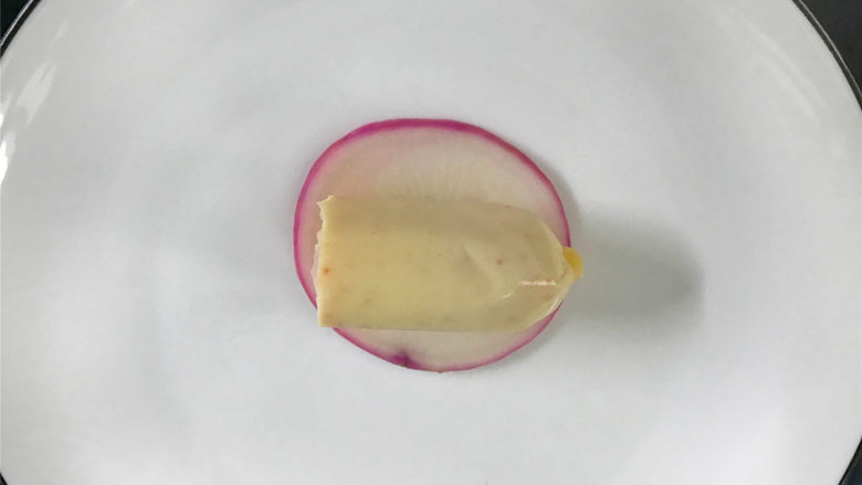 萝卜鱼籽肠卷,取一片焯好水的萝卜片,把1段鱼籽肠放在萝卜片上。