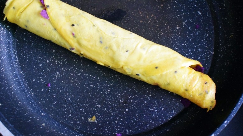 紫薯糯米鸡蛋卷,将鸡蛋饼卷起,同时在封口处抹上碗中剩余的鸡蛋糯米粉糊的残留,将口封住。