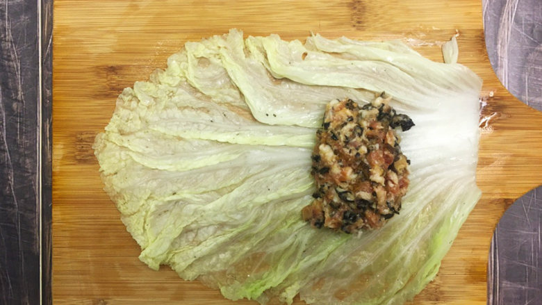 金玉白菜卷,将白菜叶铺平,放上肉馅,两边的菜叶往肉馅包上,再从下往上卷起