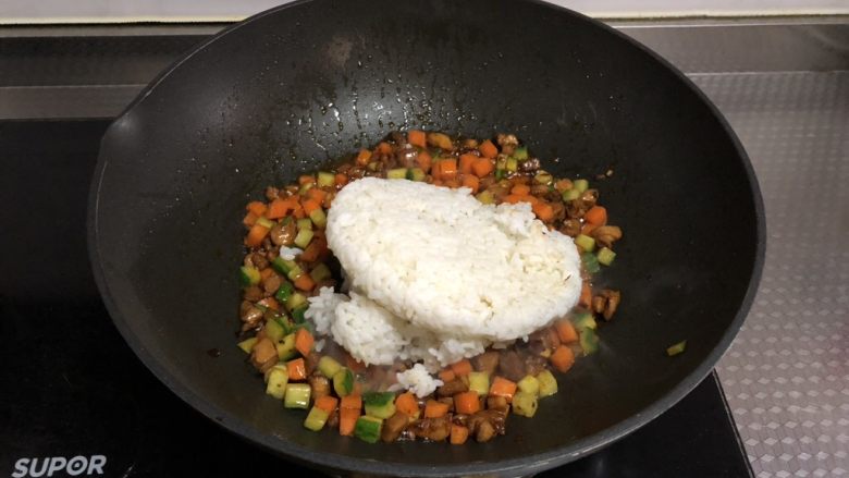 老干妈鸡丁炒饭,倒入隔夜剩饭,转小火,用铲子不停碾压翻炒至米饭无硬块