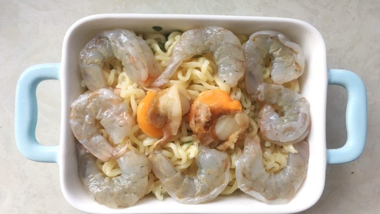 海鲜焗面,烤箱预热180度,用筷子夹出腌制好的虾仁跟扇贝,均匀的摆放在焗盘内