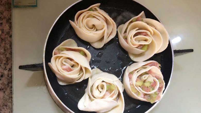 玫瑰花抱蛋煎饺,放入玫瑰花饺子,中小火煎制一分钟。倒入三分之一的水,盖上盖子焖至水干。