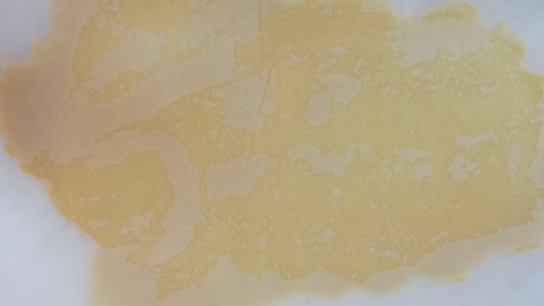 圣诞树饼干,台面上铺油纸,放上变硬的面团压扁,上面再盖上一层油纸,擀至3mm厚度即可。