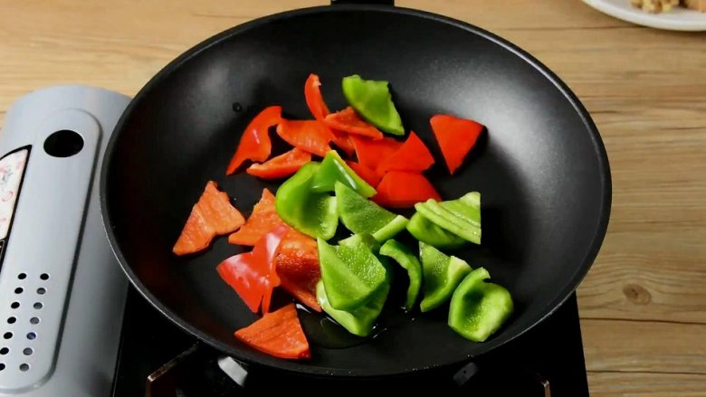 菠萝咕噜肉——水果入菜,一不小心却成了名菜,锅中倒少许油,将青红椒炒至表皮变软,盛出备用。