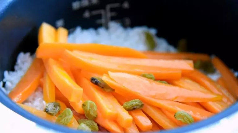 这种方法做的羊肉抓饭,相信大家一定会喜欢,跳挡后,加入一碗生米,再铺上胡萝卜、葡萄干