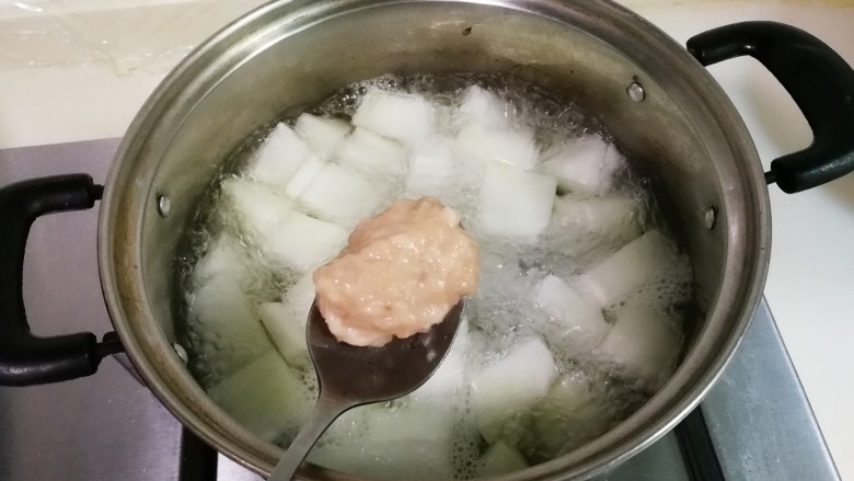 冬瓜汤汆蛋黄酱圆子,锅中放入冬瓜和适量清水烧开,调小火,勺子挖出适量肉糜,放到锅里盖上锅盖中火烧开至圆子漂浮起来