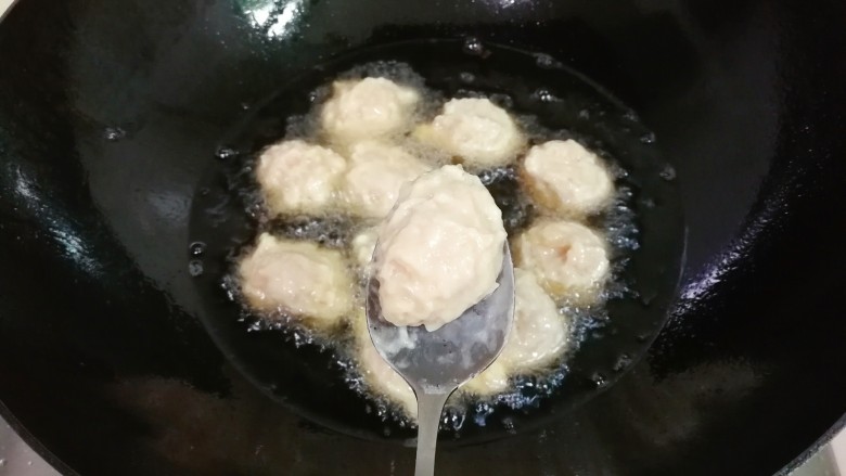 炸蛋黄酱圆子,锅中放入一大碗豆油烧热,用勺子接住手中挤出的肉糊放入锅中