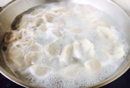 胡萝卜牛肉馅饺子,锅里放大量的水,水开后将饺子推入锅里。 一次别煮太多,我每次煮20~30个左右。
煮饺子时朝一个方向搅动,期间水开后往里倒入一小碗的凉水,这样重复3次。饺子完全浮在水面就熟了。饺子煮熟后用笊篱捞出来,控一下水分,然后装盘。
刚下锅后一定先用勺按照顺时针推水,这样饺子就不沉底,不粘锅啦。