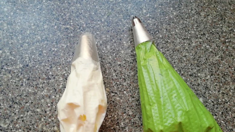 圣诞奶油蛋糕,剩下的淡奶油继续打发至9分发,取一个裱花袋装入小号圆孔裱花嘴,装入一小部分白色的奶油备用,将剩下的奶油加入绿色的色素,调出圣诞树的颜色,另外取一个裱花袋装入小号八齿裱花嘴,装入绿色的奶油备用。