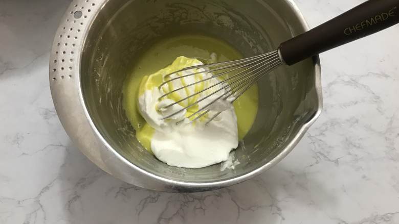 迷你圣诞树蛋糕,取三分之一的蛋白霜加入蛋黄糊中,用切拌手法搅拌均匀。