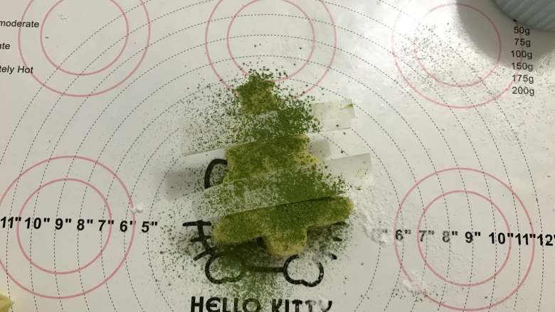 迷你圣诞树蛋糕,取两条小纸条放到蛋糕上,撒上适量抹茶粉装饰即可。