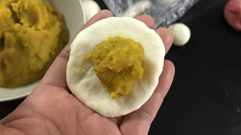 圣诞帽南瓜包,取一个大的白色面团,擀成圆面片后加入15克南瓜泥馅。