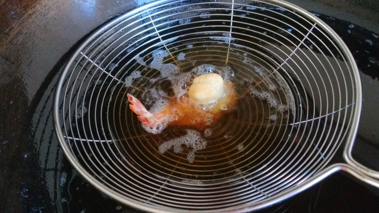 新文美食 凤还巢,在把小球蘸着糊料沾在虾身体上,放入漏勺炸制固定即可。