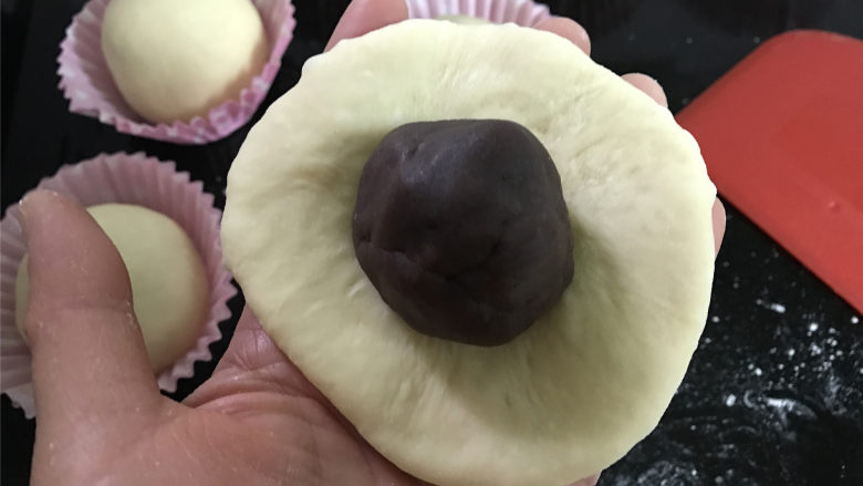 麋鹿豆沙小餐包,取一个松驰好的面团,擀成圆面片后包上一份豆沙馅。