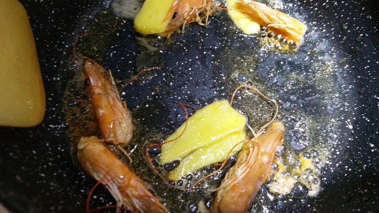 超级鲜美的海鲜粥,锅里放少量油,下生姜片和虾头去炒