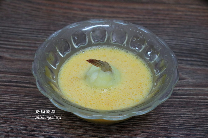 凤尾虾球,取两个鸡蛋打撒,划成细腻的蛋液,将包裹土豆泥的虾仁在鸡蛋液里滚一下。