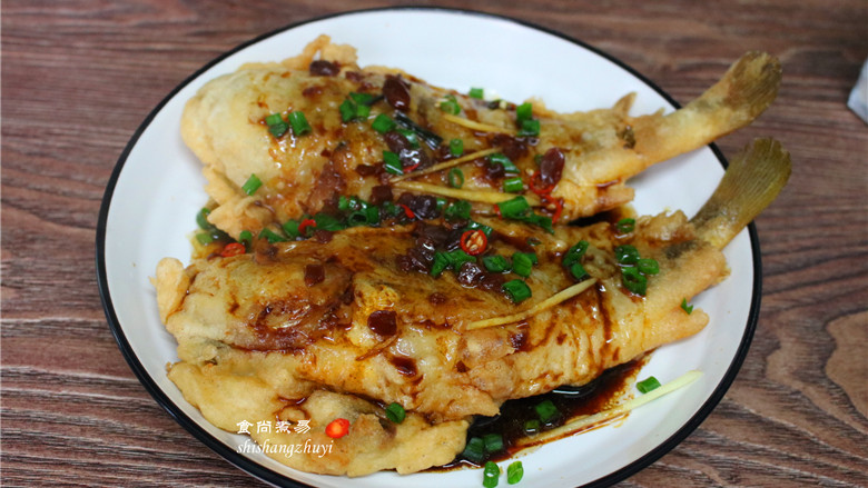 酥炸黄花鱼,鱼肉上面撒点葱花和红辣椒点缀增香,将酱汁趁热淋在鱼肉身上即可。