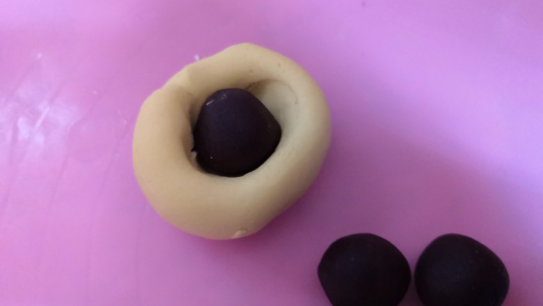 南瓜饼,取一个面团撮圆,压一个窝,放入豆沙馅。