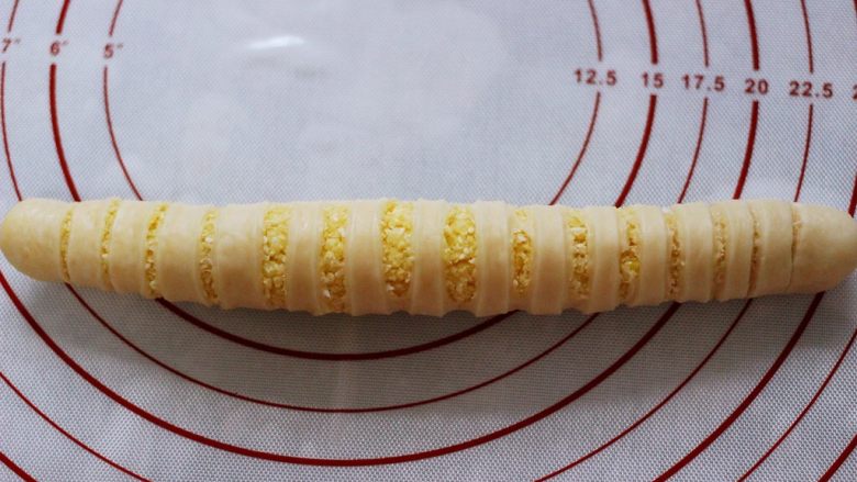 椰蓉奶香面包圈,切好后从侧面卷起,卷成长筒状底边放在下面压住,防止发酵时胀开。
