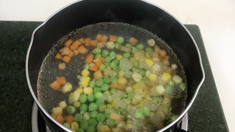 馒头蔬菜什锦沙拉,锅内加入适量清水煮沸,然后把玉米粒、胡萝卜粒和<a style='color:red;display:inline-block;' href='/shicai/ 148'>豌豆</a>一起放入煮熟。