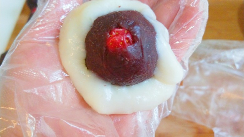 新文美食 玫瑰细沙草莓🍓大福,把豆沙草莓放在糯米上包好。