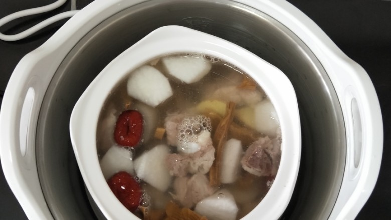 干笋萝卜排骨汤,拿出九阳桃花盏电炖锅,放入蒸格,再加入清水至水位线。把炖盅放到蒸格中间位置。
