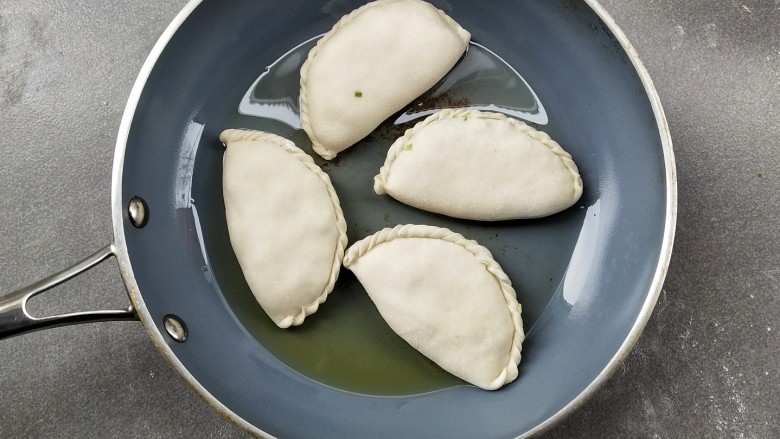 韭菜盒子,热锅倒少许的油润锅,将韭菜盒子放入,小火煎至一分钟左右,底部微黄后翻面