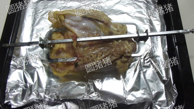 皮香肉嫩——简易版盐锔鸡,在烤盘上铺垫一张锡纸,用烤叉将鸡串起来。