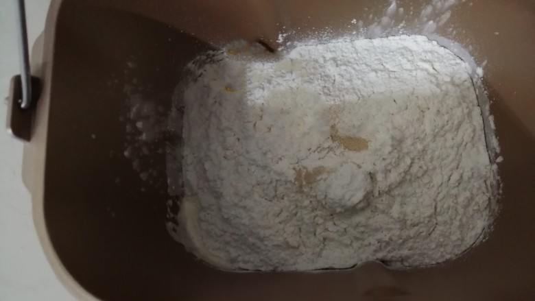 中种醇奶面包卷,倒入250克面粉和两克酵母,面包桶放入到东菱面包机里,选择一个十分钟的和面程序