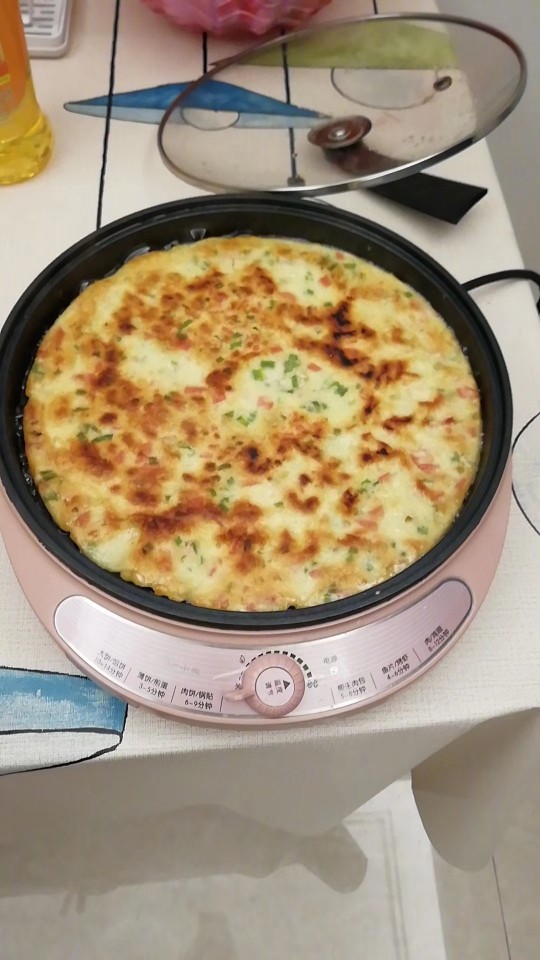 中式披萨饼,将电饼锅打开后,在锅里刷一层食用油,然后将图一调制好的面粉混合液慢慢倒入锅中,用木铲子慢慢摊平,保证整个锅底被覆盖,盖上锅盖煎五分钟,再翻来看看锅底那面煎至金黄色再翻面,煎另外一面。