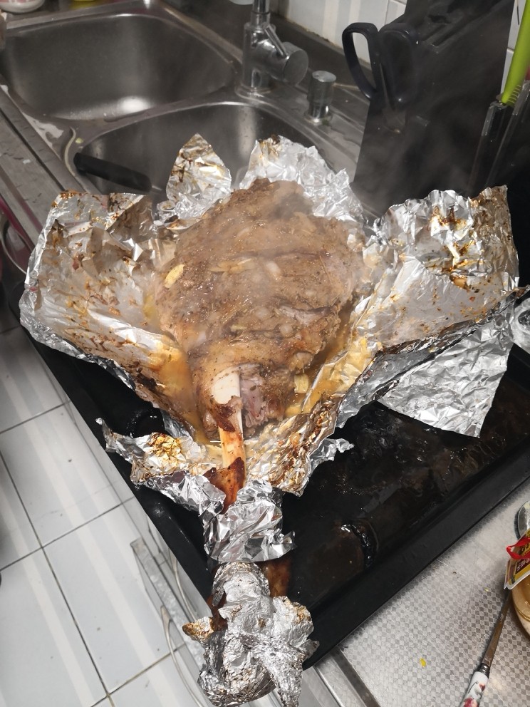 烤羊腿,40分钟后取出羊腿打开锡纸将保留下部锡纸,对羊腿进行改刀