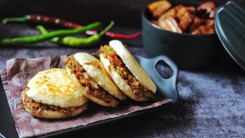齿颊留香的腊汁肉白吉馍,腊汁肉加入少许青椒剁碎,舀入一勺卤肉汤,白吉馍从中间剖开,夹入剁碎的肉。