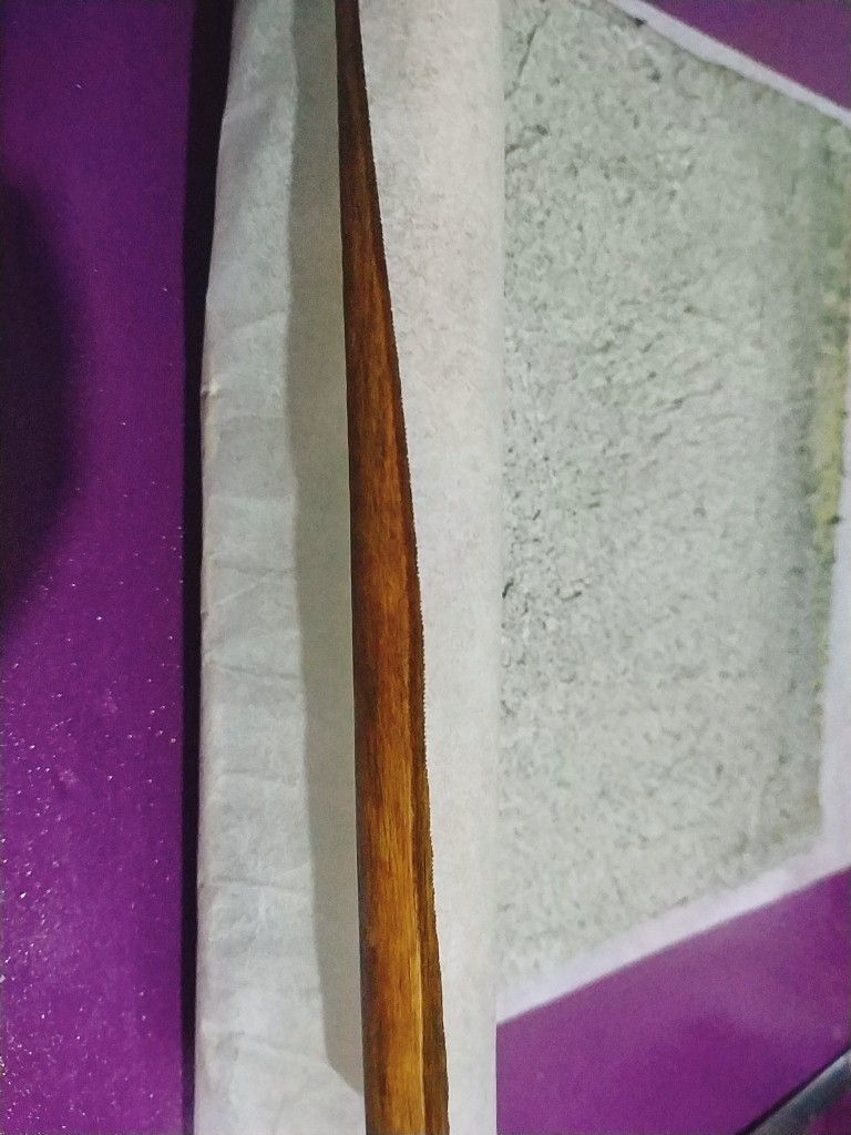黑芝麻蛋糕卷,借助擀面杖把油纸从一边慢慢卷起;