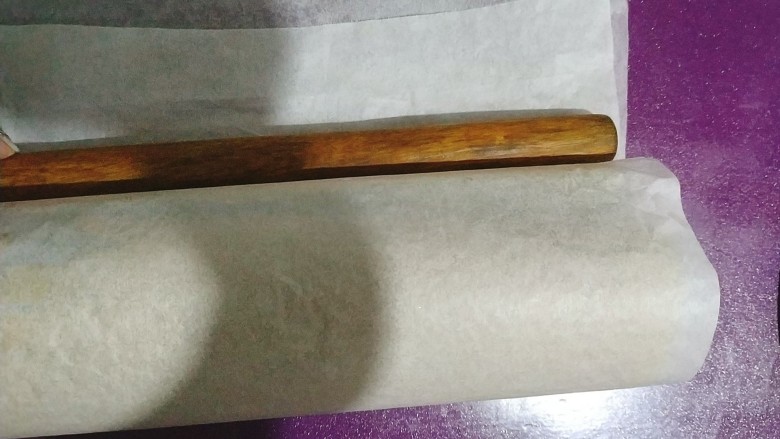 黑芝麻蛋糕卷,卷成卷后,借助擀面杖用力压并且往后推紧,让卷紧实;