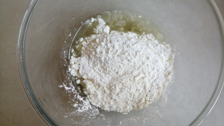古早味蛋糕,将加热后的玉米油倒入盆里,再将面粉过筛倒入