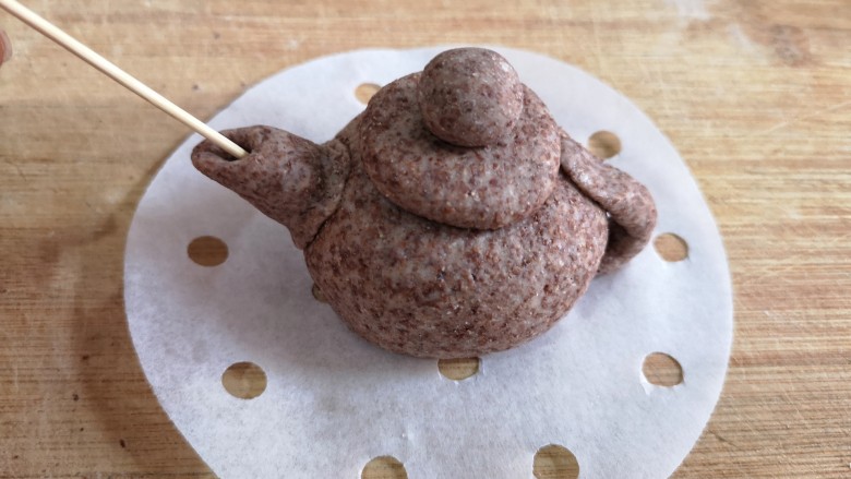 黑全麦象形粗陶茶具豆沙包,将做好的配饰用水粘在壶身上,壶嘴用牙签戳洞。
