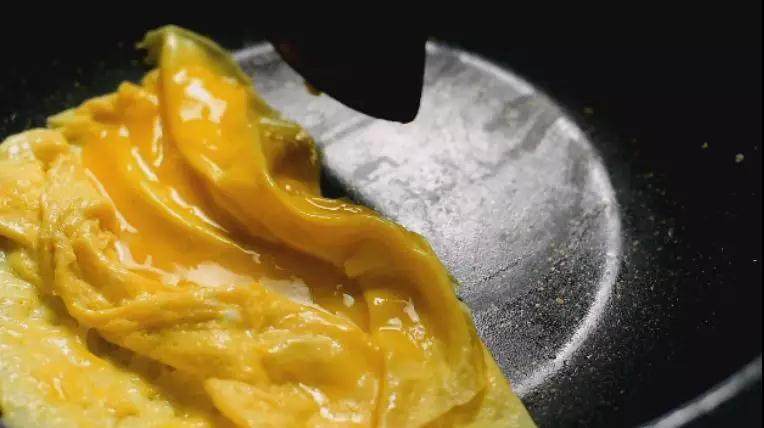 广东传统名菜黄埔炒蛋,即将凝固时用铲子推到一旁;分多次倒入蛋液,摊薄,铲起叠在一块蛋皮上盛出