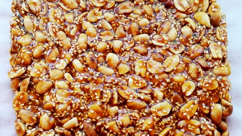 美味花生糖,倒在铺有油纸的案板上,用木铲压平