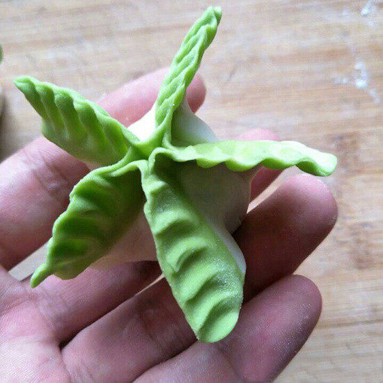 翡翠白菜饺子,再用大拇指和食指以“比心”的手势给它推压出花纹；