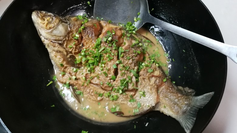 蒜末糖醋鳊鱼,翻面转中火烧至汤汁还剩下原有汤汁的三分之一,撒入青蒜末