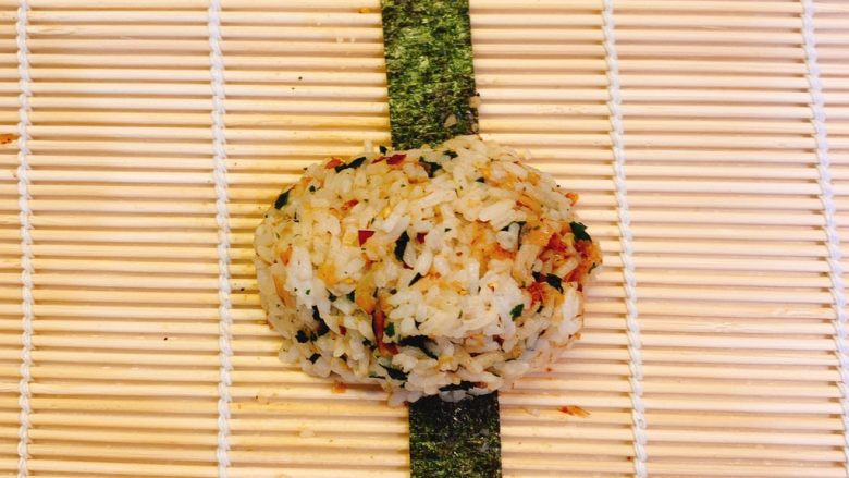 超浓郁日式饭团,在竹帘上先铺上紫菜条,再用手把饭抓成一团,放在紫菜条上面