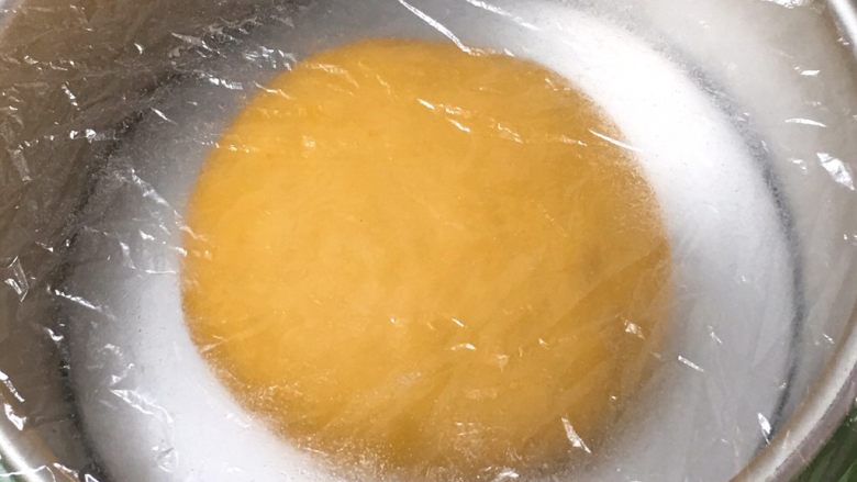 喜饼-南瓜豆沙味,厨师机揉面至面粉结团,无需出膜状态。揉面完成整理、滚圆放入模具,盖上保鲜膜。