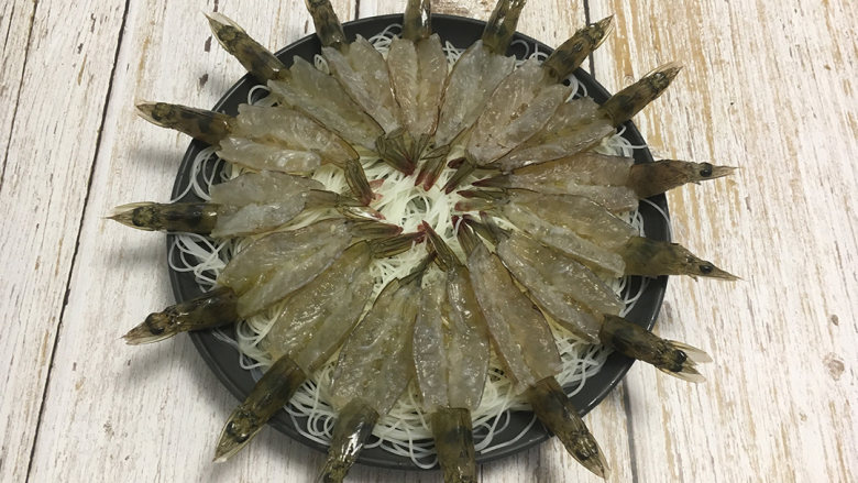 金蒜粉丝蒸虾,泡好的粉丝沥干水分切段铺在盆里,再将虾均匀的铺放在粉丝上