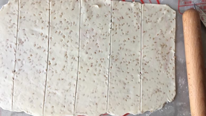 炸排叉(麻叶),取一份底下洒少许干粉擀成薄面片(特别注意:面片擀的越薄越好,炸出来的效果夜越酥脆),用刀在大面片上划出宽约9cm的长面片,再横切间距约4cm左右