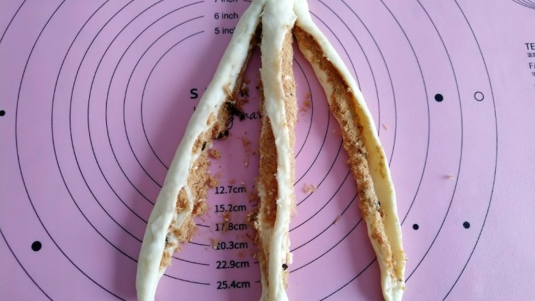 海苔肉松辫子面包,全部卷完后 取其中一个面团 从上往下划开 顶部不要划开 如图。