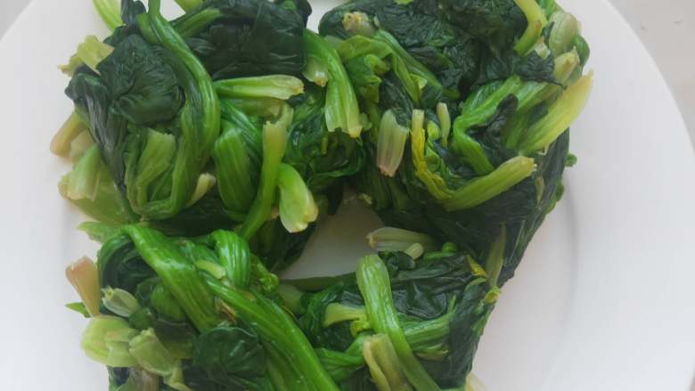 超级好吃又有营养的素炒菠菜 ,放凉的菠菜用手纂干里头的 水分,放入盘中备用。