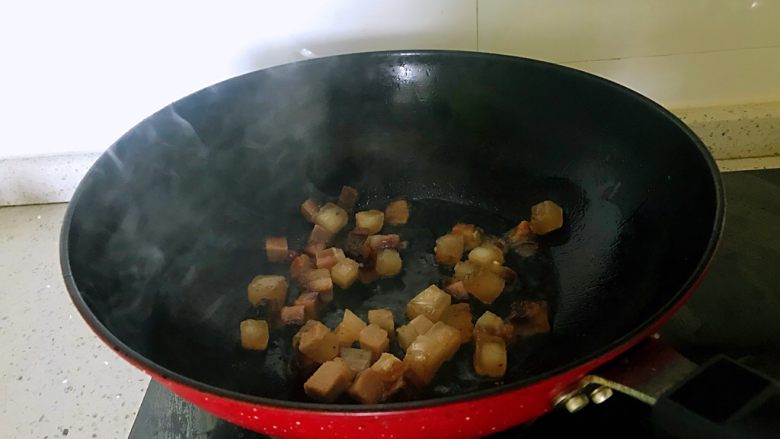 小炒腊肉丁,锅置于火上,放一点点油,下入腊肉,炒至出油。(腊肉丁中有肥肉,会有油出来)