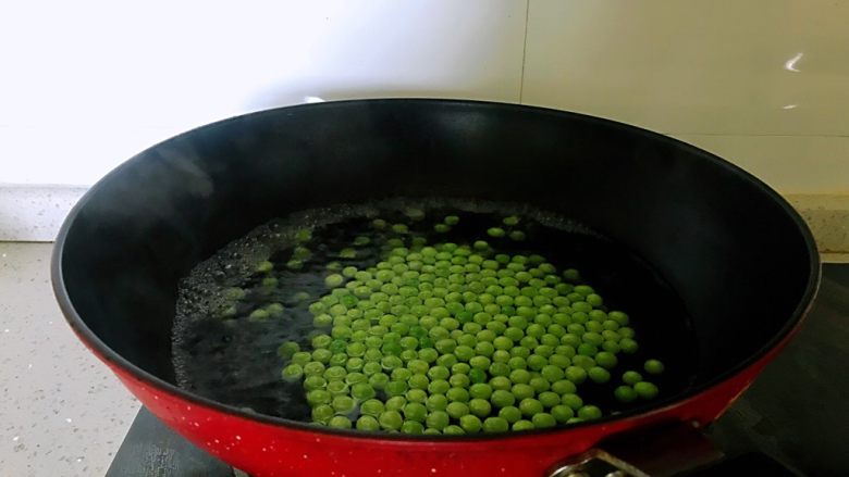 小炒腊肉丁,豌豆洗净,锅烧开水,豌豆焯水一分钟。如是冷冻豌豆,可提前放入清水中解冻。