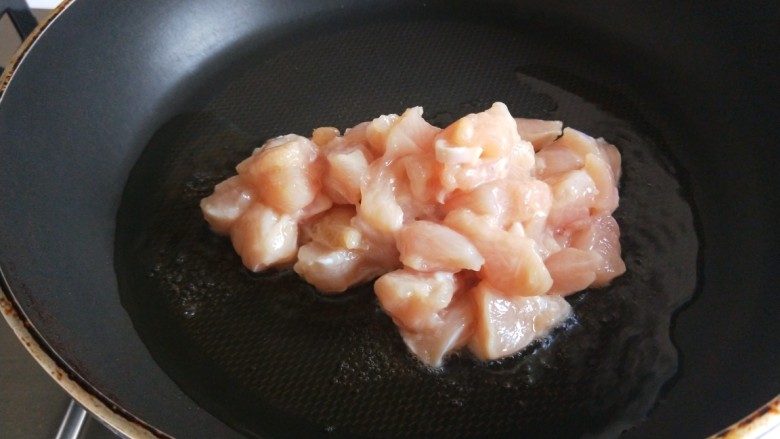 新文美食 麻辣鸡丁,平底锅烧热倒入适量油,倒入鸡丁。