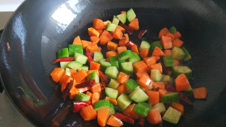 新文美食 麻辣鸡丁,倒入胡萝卜黄瓜丁翻炒均匀。
